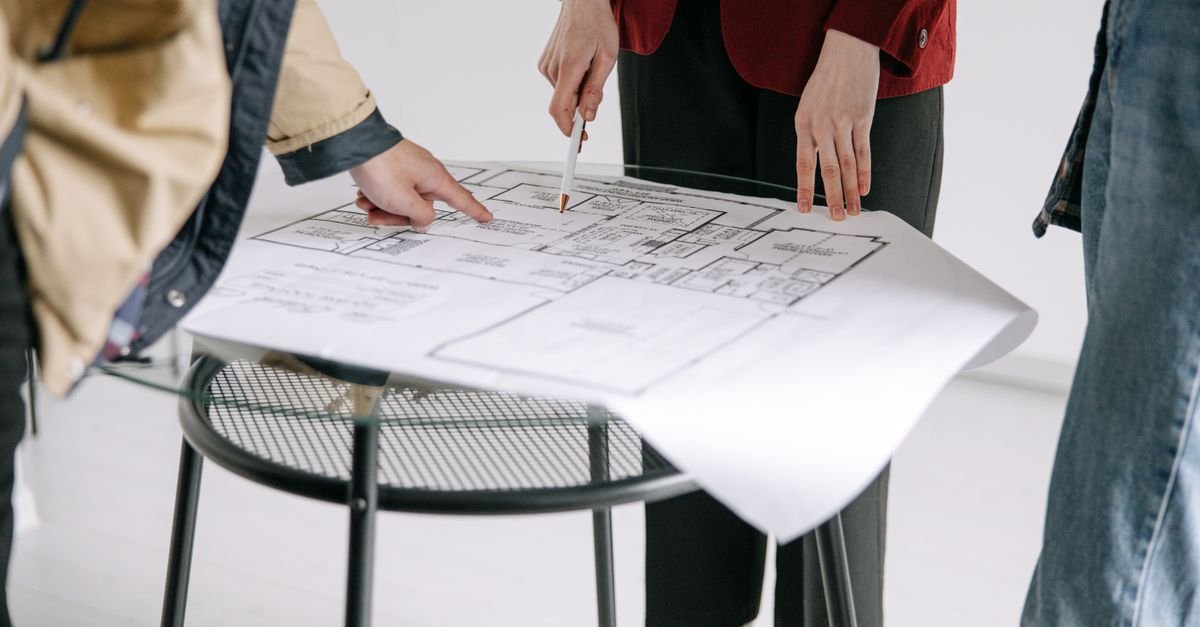Deux personnes examinent un plan d'architecte posé sur une table de travail